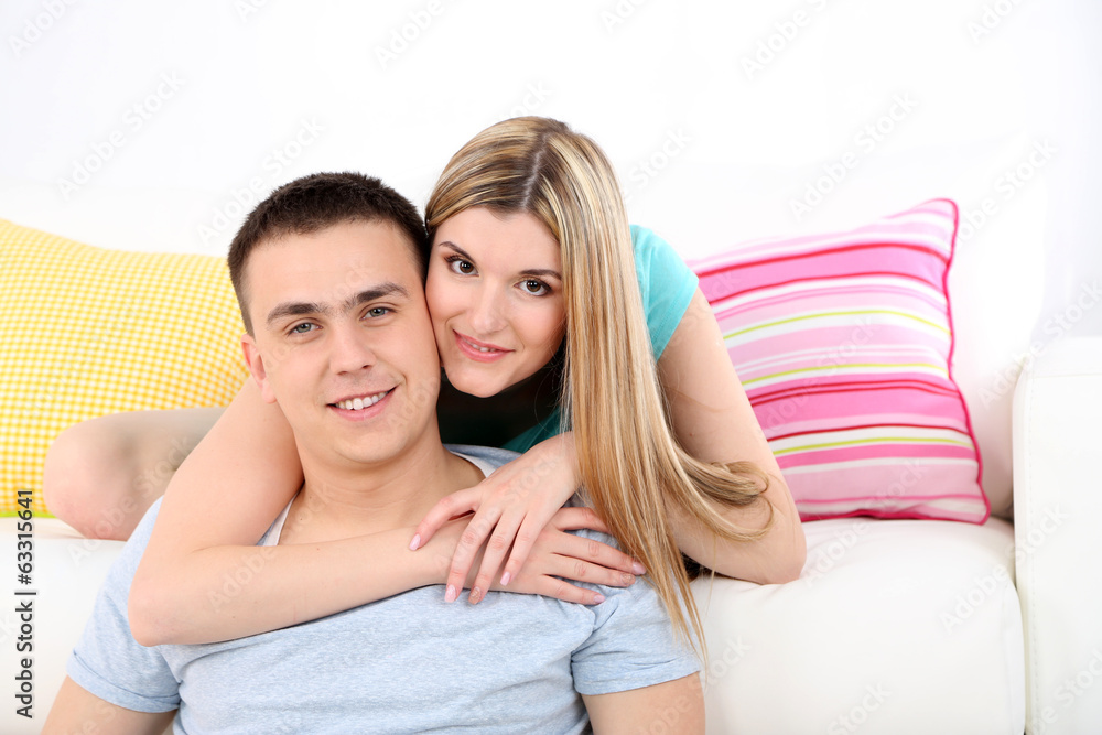 Loving couple sitting on sofa, on home interior background Loving couple sitting on sofa, on home interior background