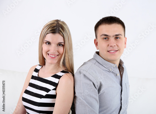 Loving couple sitting on sofa, on light background