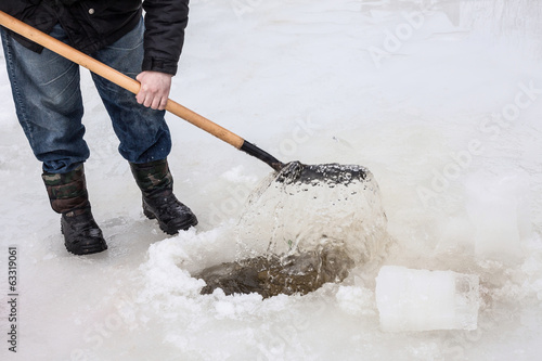 man scoops chunks of ice out of the hole © zadveri