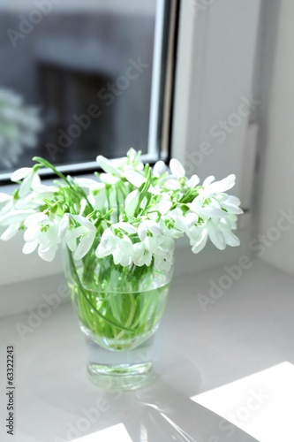 Beautiful bouquets of snowdrops in vases on windowsill