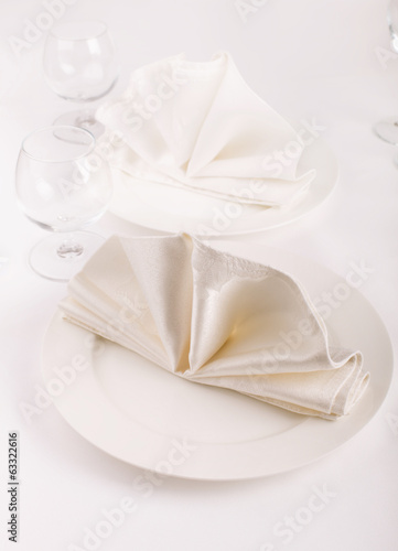 Table appointments with plates, napkins and wine glasses