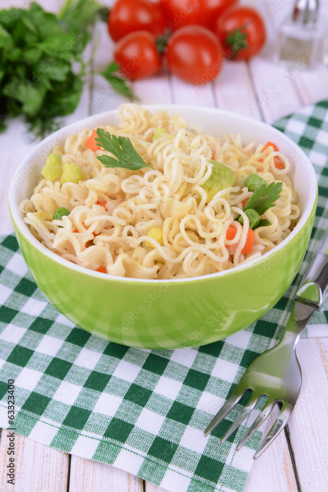 Tasty instant noodles with vegetables in bowl on table close-up Tasty instant noodles with vegetables in bowl on table close-up