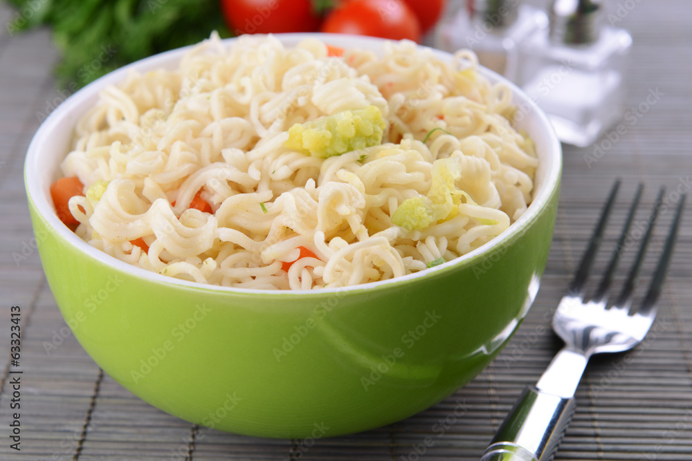 Tasty instant noodles with vegetables in bowl on table close-up Tasty instant noodles with vegetables in bowl on table close-up