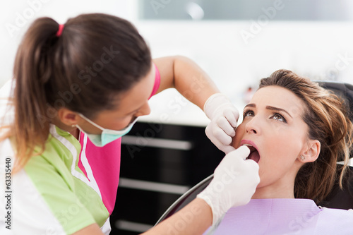 Woman dentist checking her patient s teeth