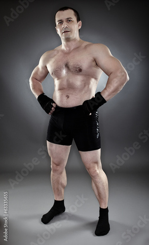 Shirtless athletic muscular man standing akimbo