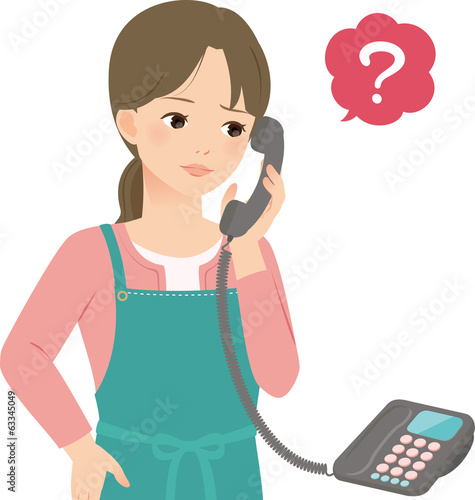 電話に出て不審そうなエプロン姿の女性