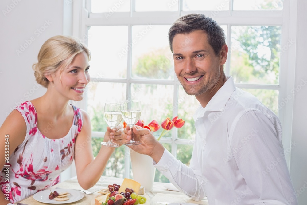 Happy young couple toasting wine glasses over food Happy young couple toasting wine glasses over food