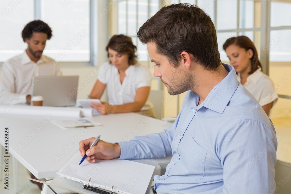 Businessman reading document with colleagues in meeting at offic Businessman reading document with colleagues in meeting at offic