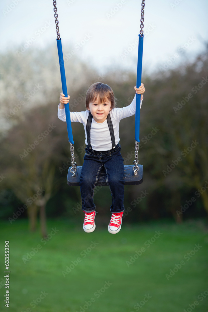 Sweet little boy, swinging in a park
