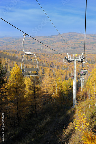 Chair lift with pillars against autumn mountain forest photo