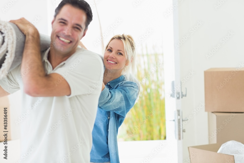 Fototapeta premium Couple carrying rolled rug after moving in a house
