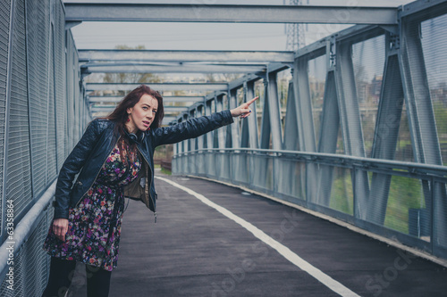 Pretty girl with long hair hitchhiking on a bridge