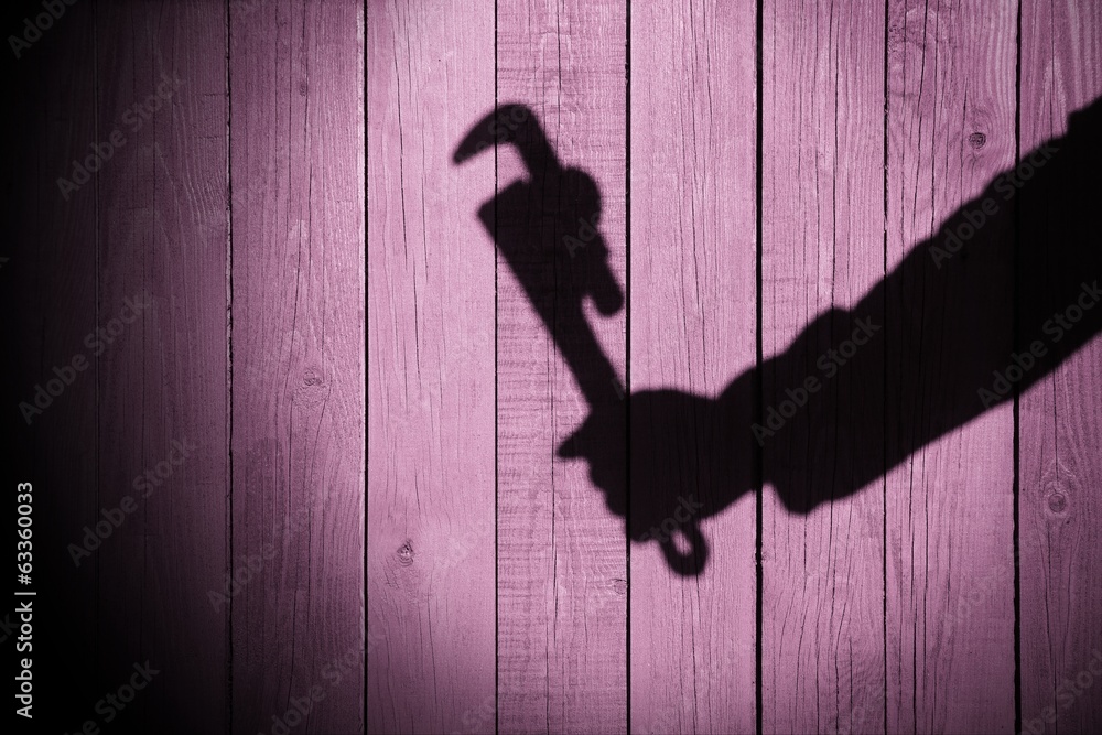 Human hand shadow with adjustable wrench on the wood background Human hand shadow with adjustable wrench on the wood background
