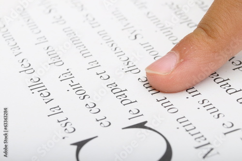 Child reading with his finger on dictionary photo