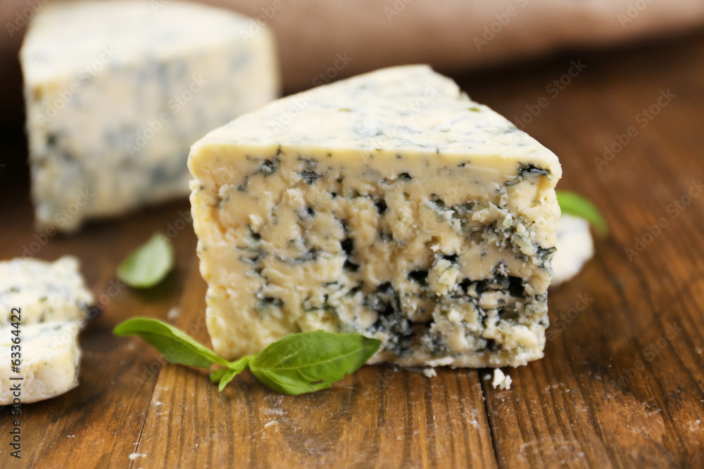 Tasty blue cheese with basil, on wooden table Tasty blue cheese with basil, on wooden table