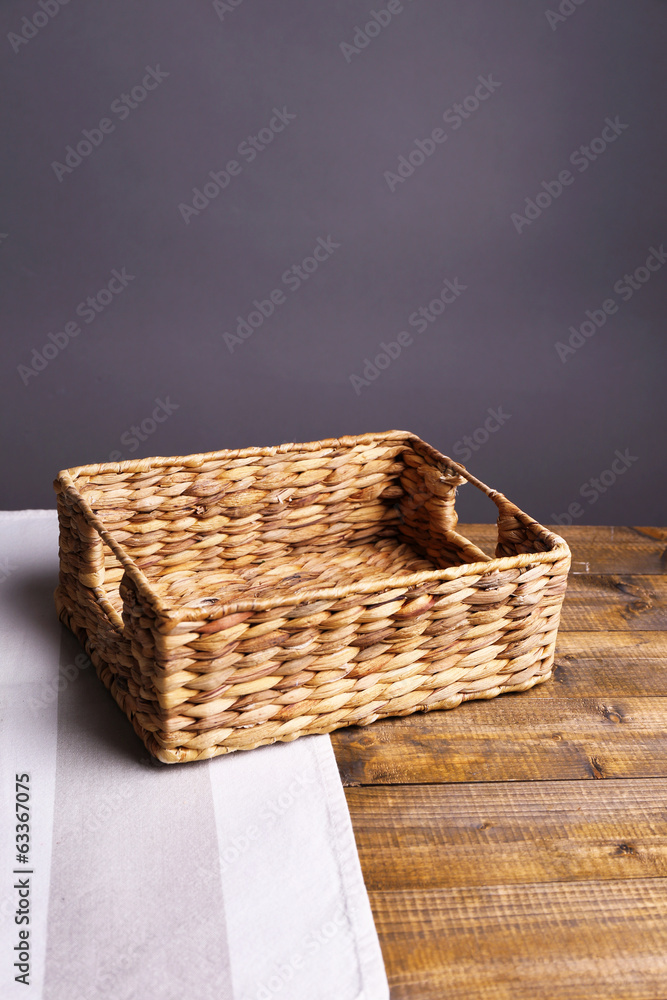 Empty wicker basket on wooden table, on dark background Empty wicker basket on wooden table, on dark background