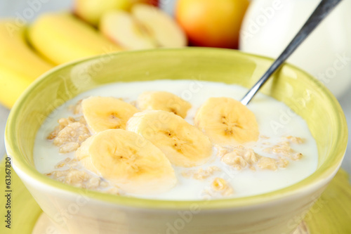 Tasty oatmeal with bananas and milk on table close up