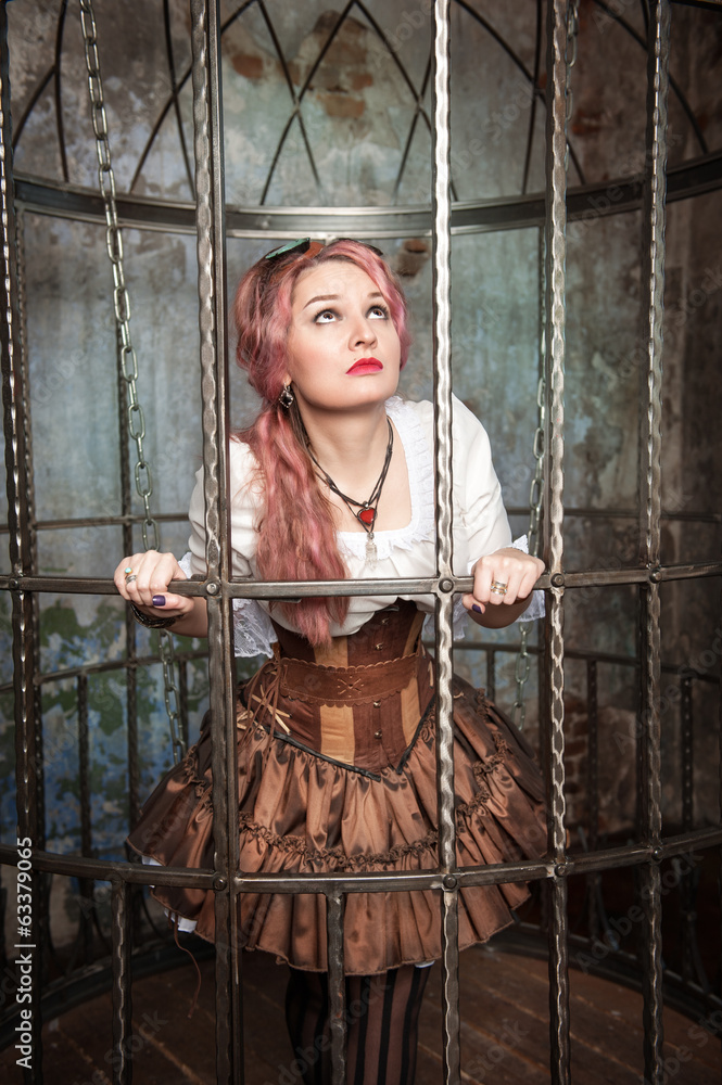 Frightened beautiful steampunk woman in the cage
