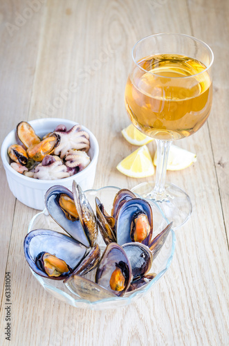 Mussels with a glass of white wine on the wooden table