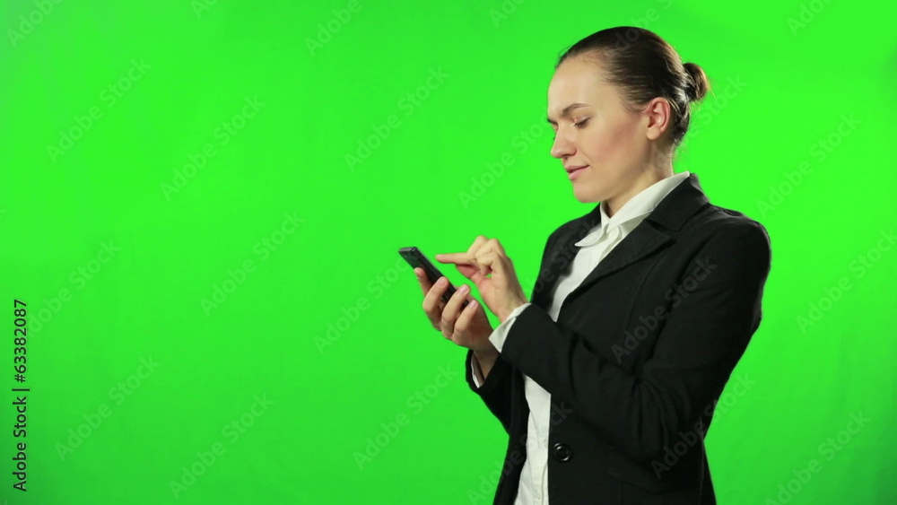 Woman dialing on her phone against a green background Woman dialing on her phone against a green background