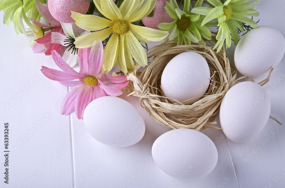 Flowers and raw eggs on light background