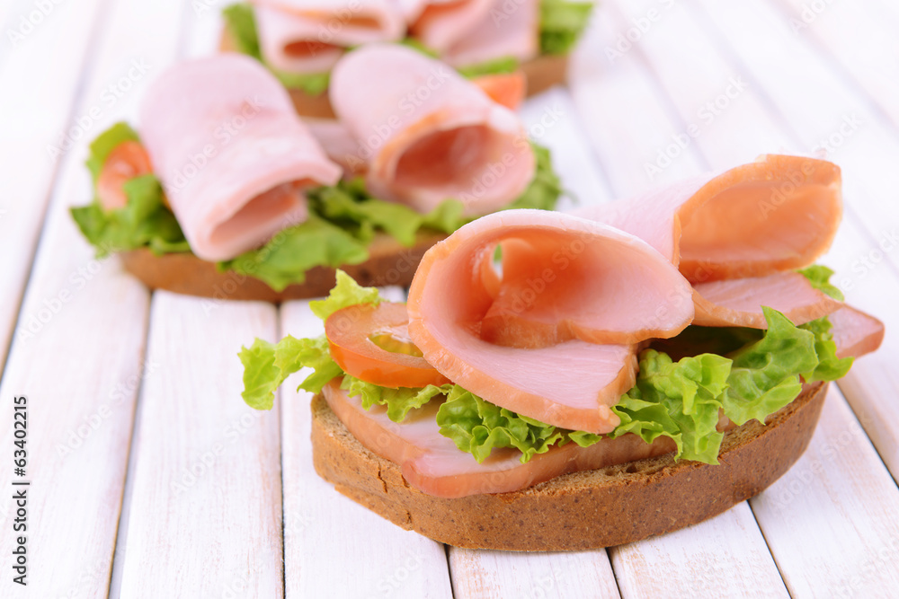 Delicious sandwiches with lettuce and ham on table close-up