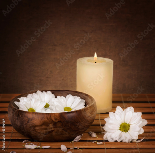 Spa decoration with candle and daisies floating in water