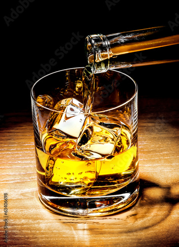 Pouring whiskey drink into glass