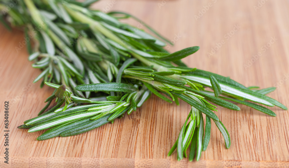 Rosemary branch on a chopping wooden board Rosemary branch on a chopping wooden board