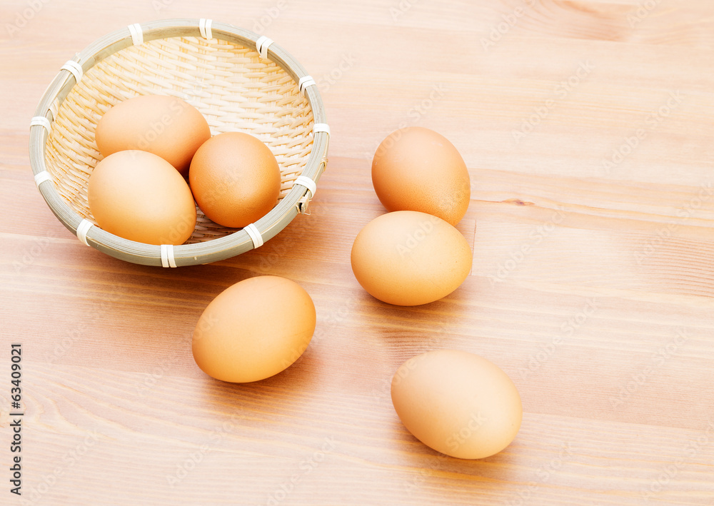 Brown egg in basket over wooden texture Brown egg in basket over wooden texture