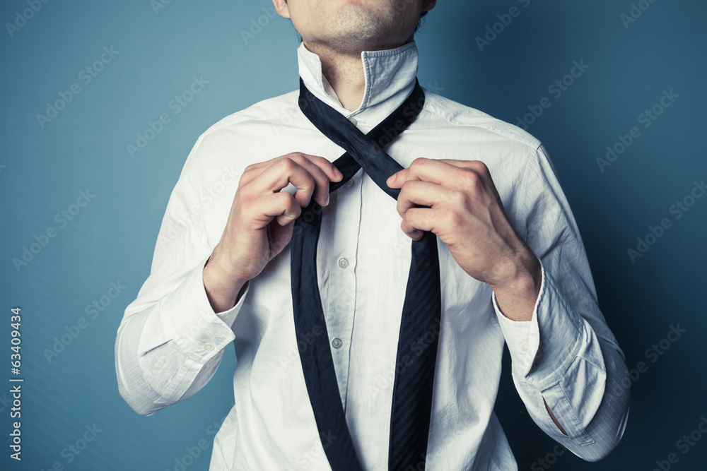 Young man tying his tie - obrazy, fototapety, plakaty 