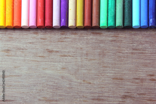 Crayons lined up in rainbow isolated on wood background