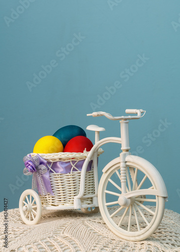 The bike with colored eggs in the basket on a blue background