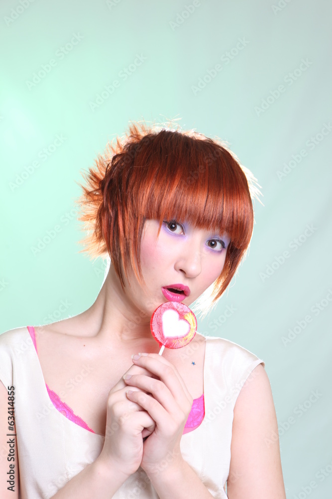 cheerful girl with lollipop in shape of heart on light backgroun