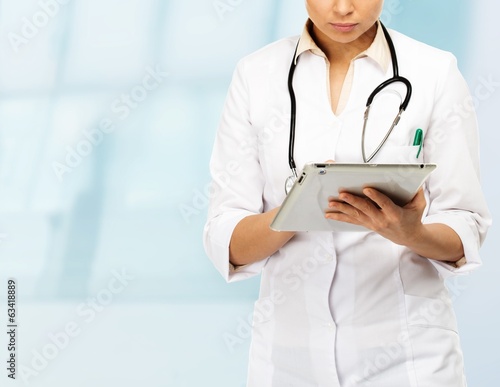 Young brunette doctor woman taking notes on tablet pc