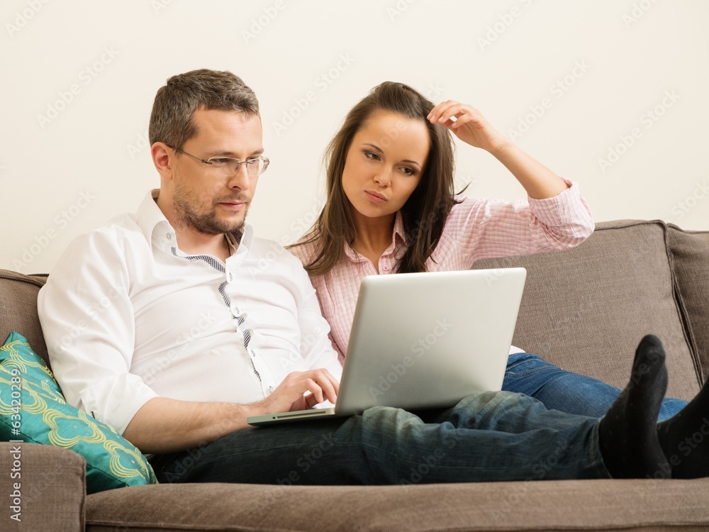 Young couple with laptop on a sofa in home interior