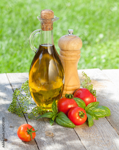 Olive oil bottle, pepper shaker, tomatoes and herbs