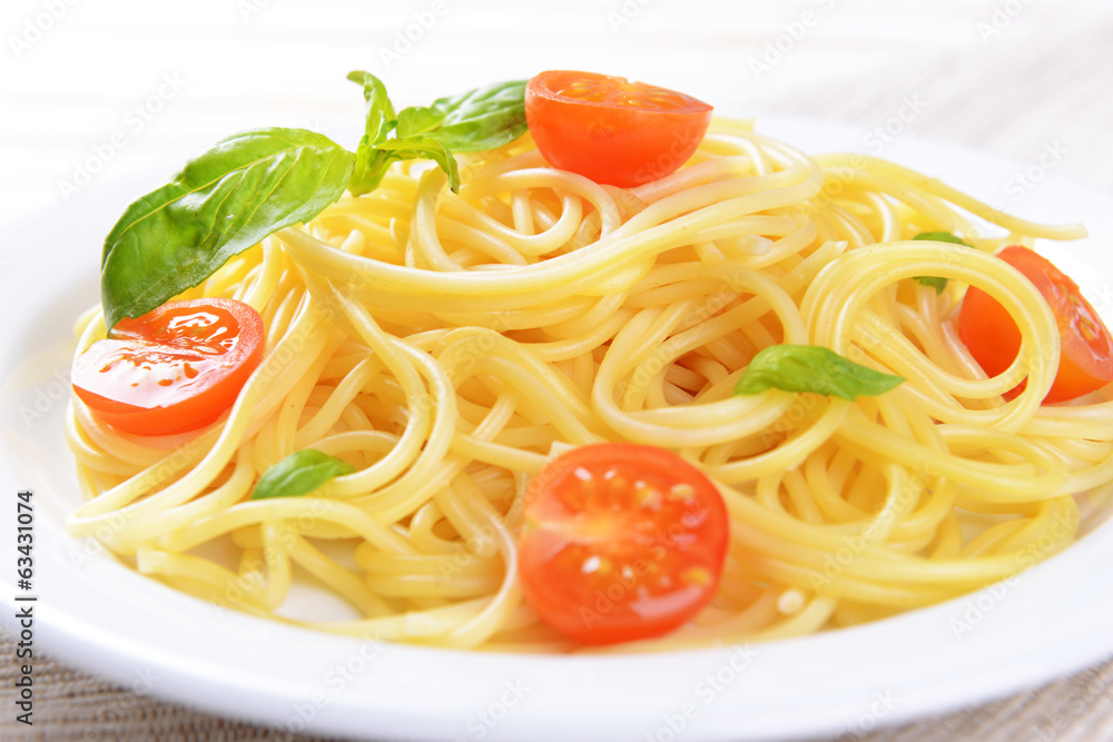 Delicious spaghetti with tomatoes on plate on table close-up Delicious spaghetti with tomatoes on plate on table close-up