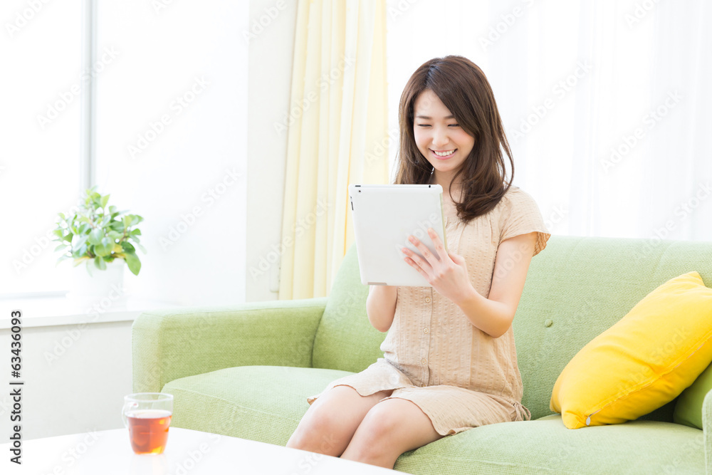 部屋でタブレットを見る女性 部屋でタブレットを見る女性