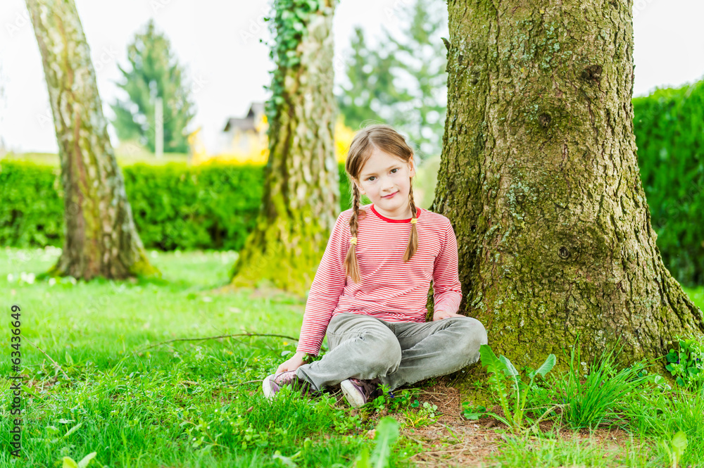 Adorable little girl sitting under the tree Adorable little girl sitting under the tree
