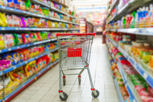Supermarket interior, empty red shopping cart. © hxdyl