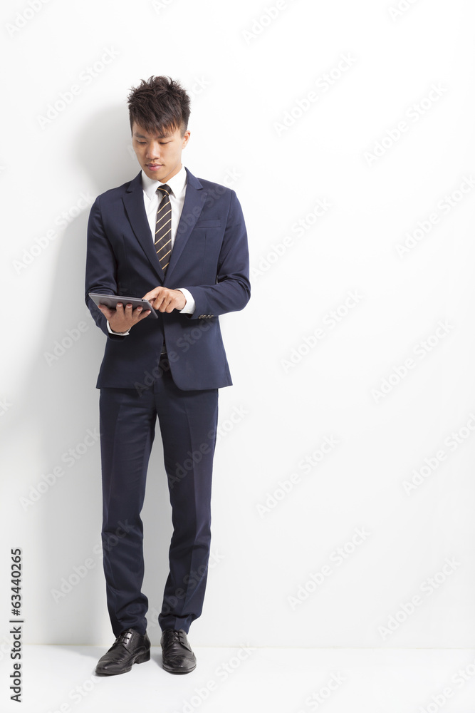 businessman using tablet and standing front of wall businessman using tablet and standing front of wall