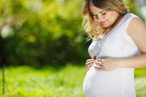 Portrait Healthy pregnant woman sitting on green grass