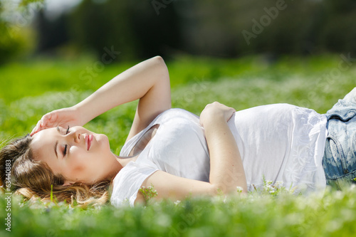 Portrait of a pregnant woman lying on green grass in the park