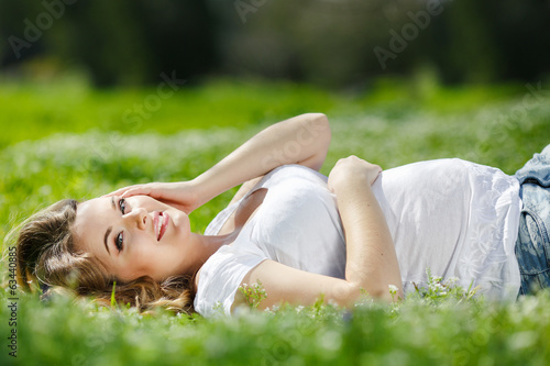 Portrait of a pregnant woman lying on green grass in the park