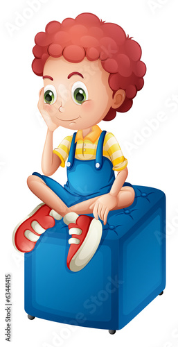 A young boy sitting above the blue chair