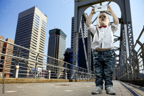 Boy with gadget on the bridge in the city of skyscrapers
