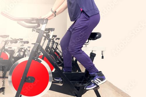 Woman energetically riding exercise bike in gym