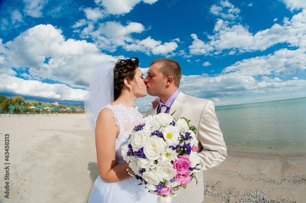 Young and beautiful bride and groom on the beach in summer Young and beautiful bride and groom on the beach in summer
