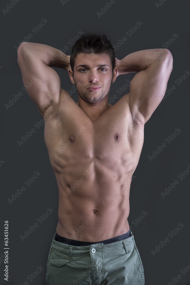 Muscular young bodybuilder showing biceps and ripped abs Muscular young bodybuilder showing biceps and ripped abs